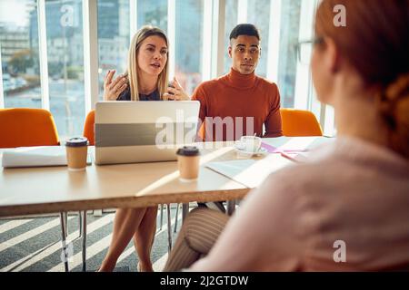 De jeunes collègues d'une commission expliquent un poste à une candidate dans une atmosphère agréable au cours d'une entrevue pour un emploi. Entreprise, Banque D'Images