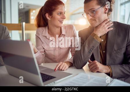 Deux jeunes collègues d'affaires dans une atmosphère conviviale au bureau discutent tout en regardant ensemble un contenu d'ordinateur portable. Entreprise, personnel, bureau, Banque D'Images