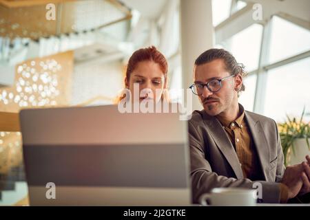 Deux jeunes collègues d'affaires dans une atmosphère de travail au bureau discutant du contenu d'un ordinateur portable. Entreprise, personnel, bureau, entreprise Banque D'Images