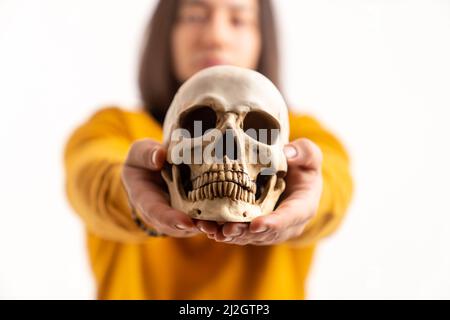 Portrait d'un modèle de crâne de squelette tenu par un homme caucasien portant un sweat-shirt jaune. Isolé sur fond blanc. . Photo de haute qualité Banque D'Images