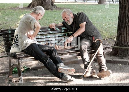 SOFIA, BULGARIE - 02 AOÛT 2017 : deux hommes d'âge moyen assis sur un banc et jouant un match d'échecs dans un jardin de la ville de Sofia Banque D'Images