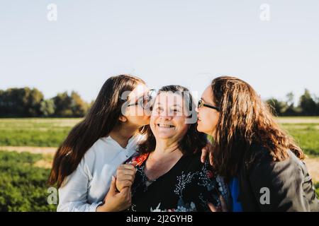 Femme famille souriant et embrassant sur le terrain lors d'une journée ensoleillée après-midi. Fête des mères. Banque D'Images