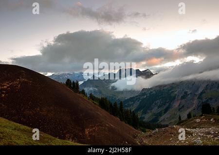 WA21288-00...WASHINGTON - nuages qui s'élève des basses terres au lever du soleil à White Chuck Cinder Cone dans la région sauvage de Glacier Peak. Banque D'Images