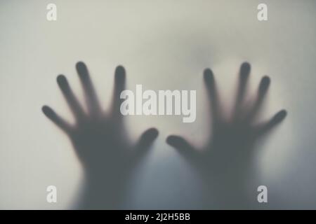 Atteindre à travers la brume. Prise de vue avec effet de flou d'une paire de mains en se retouchant sur un arrière-plan ordinaire. Banque D'Images