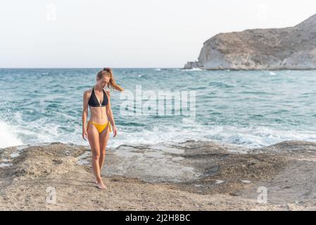 femme en maillot de bain pensant et se déplaçant le long de la plage Banque D'Images