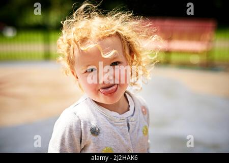 Elle peut aussi être un peu tricherie. Portrait d'une adorable petite fille qui colle sa langue à l'extérieur. Banque D'Images