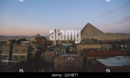 Vue sur les pyramides de Gizeh depuis la ville le soir Banque D'Images