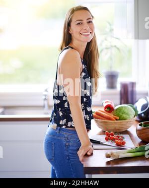 Je me sens aussi bien que je mange. Prise de vue d'une jeune femme préparant un repas dans sa cuisine. Banque D'Images