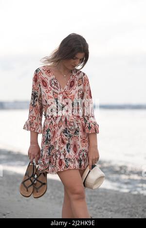 Jeune femme marchant pieds nus sur une plage de sable. Banque D'Images