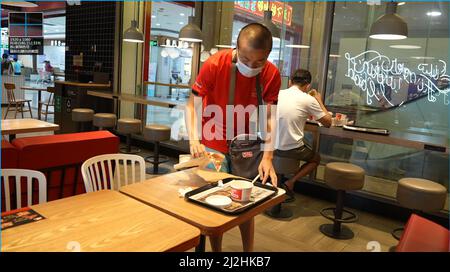 Haikou, province chinoise de Hainan. 23rd mars 2022. Chen Xingrong nettoie les tables à manger dans un restaurant de Haikou, dans la province de Hainan, au sud de la Chine, le 23 mars 2022. POUR ALLER AVEC 'China Focus: Adolescent avec l'autisme nains vers la victoire' Credit: Wang Junfeng/Xinhua/Alay Live News Banque D'Images