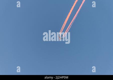 Avion dans un ciel bleu sans nuages avec des contrails colorés sans nuages pendant le coucher du soleil et l'heure d'or, Allemagne Banque D'Images