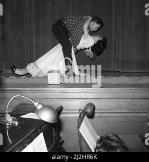 1960s, historique, deux acteurs, un homme et une femme sur scène - en gros plan - et- personel - lors d'une représentation de la comédie musicale américaine Oklahoma, produite par la Kelty musical Association à Carnegie Hall, Dufermline, Fife, Écosse, Royaume-Uni. Basé sur la pièce de 1931, 'Green Grow the Lilacs', Oklahoma est la première comédie musicale écrite par Rodgers et Hammerstein, qui a ouvert sur Broadway en 1943. Basé sur les romances d'une simple fille de ferme, la comédie musicale est un choix populaire pour les écoles et les groupes communautaires à exécuter. Banque D'Images