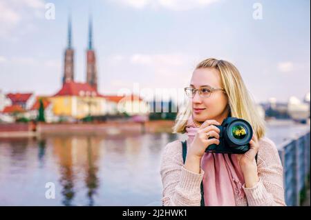 Vacances dans la ville européenne. Bonne femme blonde dans des verres roses avec photo photo photographs paysage urbain. Concept du tourisme. Banque D'Images