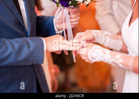 Cérémonie de mariage. Mariée mettant un anneau doré sur le doigt de la chambre de gros plan. Mariage anneaux de change vows. Banque D'Images