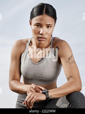 Cette montre ne se contente pas de dire l'heure. Photo d'une jeune femme sportive qui vérifie sa montre intelligente tout en faisant de l'exercice à l'extérieur. Banque D'Images