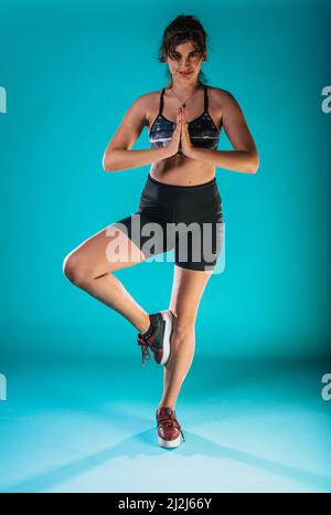 Une femme aux cheveux sombres s'encadre dans un short sportif et fait de la gym et s'étire les jambes Banque D'Images