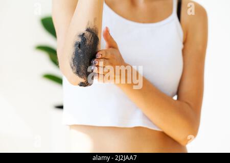 La femme nettoie la peau du corps avec un gommage au café dans la salle de bains. Banque D'Images