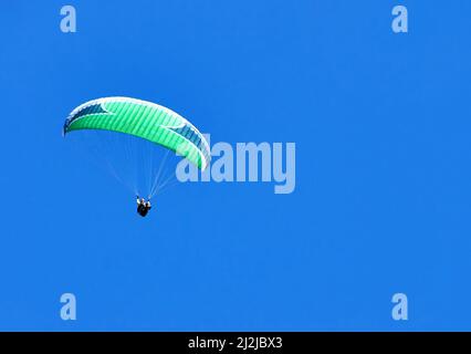 Parapente unique volant dans le ciel bleu. Concept de loisirs actifs Banque D'Images