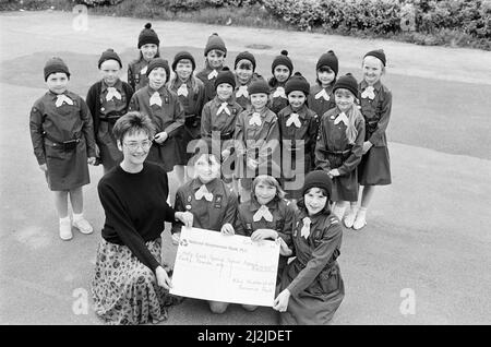 Aider les autres... ces membres de 82nd Huddersfield (église St Barnabas) Brownies, Crosland Moor, ont recueilli £40 pour l'appel de l'école Holly Bank. Sarah Goulding, Emma Trescott et Anna Evans sont photographiées pour présenter un chèque à Mary Stanesby. L'argent était le produit d'une soirée café et la vente de plantes, cartes de voeux, gâteaux et bric-a-brac dans la salle de l'église St Barnabas. 6th juin 1988. Banque D'Images