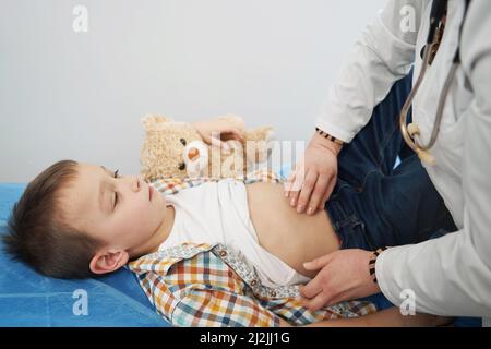 Médecin examinant l'enfant et faisant la palpation abdominale Banque D'Images