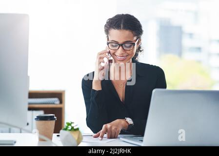 Appeler les clients pour les tenir bien informés. Photo d'une jeune femme d'affaires parlant sur un téléphone portable tout en travaillant dans un bureau. Banque D'Images