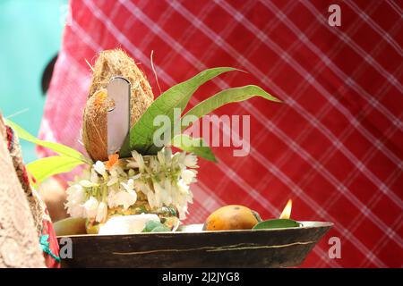 Plaque de laiton avec une petite noix de coco placée sur son dessus avec quelques feuilles comme une sorte de pratique traditionnelle Banque D'Images