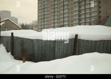 Clôture dans la neige. Zone enneigée. Ville après les chutes de neige. Vue sur le village. Banque D'Images