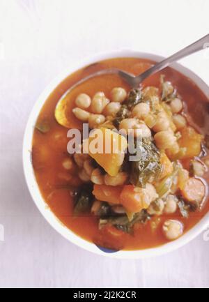 Vue panoramique sur un bol de soupe maison de pois chiches, d'épinards, de morue, de carottes et de potiron Banque D'Images