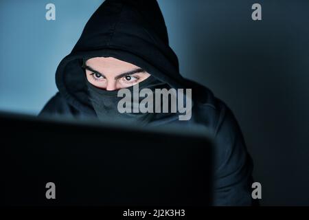 HES à la recherche de vos mots de passe. Photo d'un jeune hacker utilisant un ordinateur tard dans la nuit. Banque D'Images