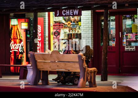 Homme sans-abri portant un chapeau de cowboy soufflant son nez devant un magasin de tabaco dans le centre-ville de Scottsdale, Arizona, États-Unis. Banque D'Images