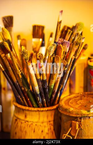 Assortiment de pinceaux usagés sur fond jaune pâle. Banque D'Images