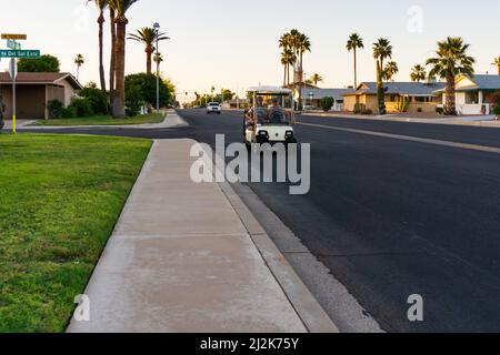Un vieux couple conduit une voiturette de golf dans une grande rue de Sun City, Arizona, États-Unis Banque D'Images