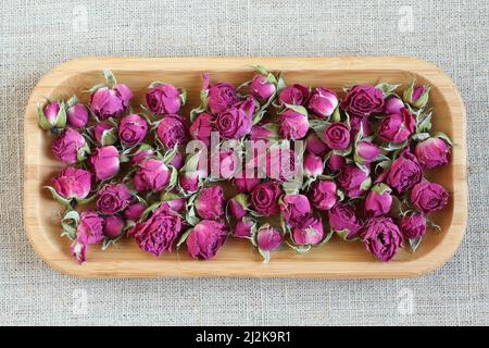 Fleurs de rose séchées sur une assiette en bois. Vue de dessus. Gros plan. Banque D'Images