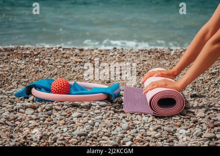 Pilates anneau magique et bande en caoutchouc sur tapis de yoga près de la mer.Concept de yoga de fitness féminin.Harmonie et méditation saines de style de vie. Banque D'Images