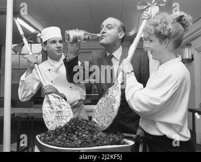 Sir John Hall, promoteur immobilier (chevalier 1991) et président à vie et ancien président du club de football de Newcastle United (1992 à 1997), photographié au Wynyard Hall Estate, comté de Durham, 16th novembre 1988. Notre image montre ... stagiaire commis chef Richard Kirton 18 et stagiaire avant de la maison Claire Marron 17, mélanger un géant de Noël pud, comme John Hall teste l'eau-de-vie à utiliser. Il va apprécier un bon goût lors d'un dîner spécial de la veille de Noël avec 50 familles et des amis proches. Banque D'Images