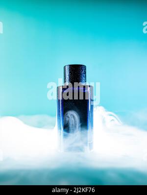 bouteille bleue d'eau parfumée sur fond bleu avec éléments de fumée Banque D'Images