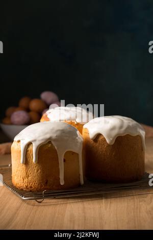 Trois gâteaux de Pâques rudes avec glaçure blanche sur fond sombre Banque D'Images