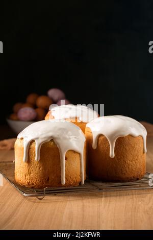 Trois gâteaux de Pâques rudes avec glaçure blanche sur fond sombre Banque D'Images