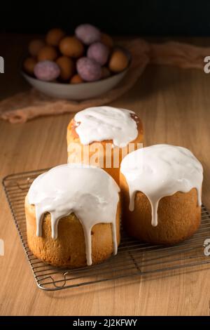 Trois gâteaux de Pâques rudes avec glaçure blanche sur fond sombre Banque D'Images