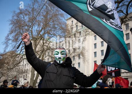 Londres, Royaume-Uni. 2 avril 2022. Un homme portant un masque agite un drapeau de groupe hacktiviste anonyme à l'extérieur de Downing Street où les gens se sont réunis pour protester contre l'augmentation du coût de la vie dans le pays. Crédit : Kiki Streitberger/Alay Live News Banque D'Images