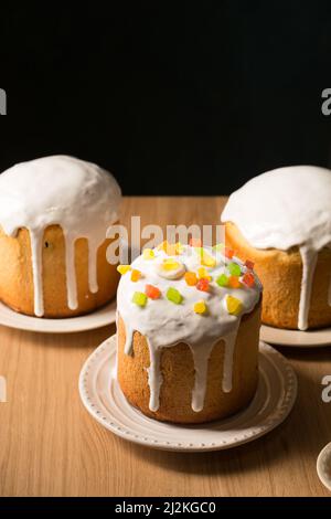 Trois gâteaux de Pâques rudes avec glaçure blanche sur fond sombre Banque D'Images
