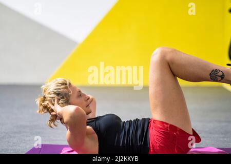 Véritable jeune femme caucasienne mature dans un sport porter dans une salle de gym faire des croquons sur un tapis. Concept de fitness. Banque D'Images