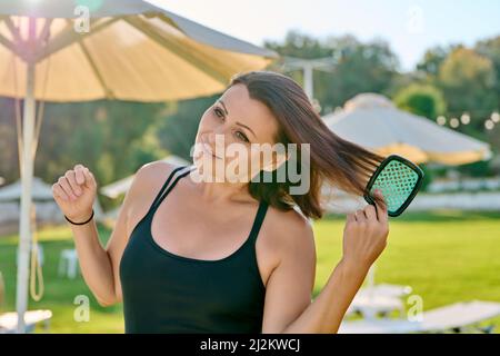 Mature belle femme en maillot de bain relaxant en été, peignant ses cheveux avec peigne Banque D'Images