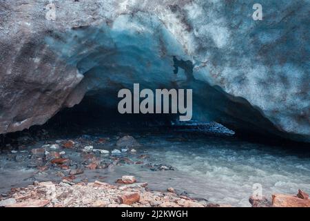 Sortie de la grotte de glace bleue sculptée dans le glacier de Vallelunga traversé par un ruisseau Banque D'Images