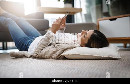 Rencontrer de nouvelles personnes en ligne. Photo d'une belle jeune femme utilisant son téléphone portable tout en se relaxant à la maison. Banque D'Images
