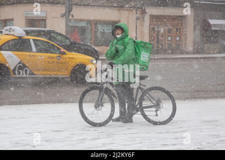 Moscou, Russie. 2nd avril 2022. Un service de livraison de nourriture par messagerie 'Delivery Club' livre une commande sur la rue Tverskaya dans le centre de Moscou pendant une tempête de neige, en Russie. Banque D'Images