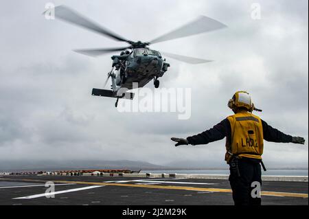 OCÉAN PACIFIQUE (31 mars 2022) Aviation Boatswain’s Mate (Handling) Airman Garrett Solomon, originaire d’Ewa Beach, Hawaii, affecté au navire d’assaut amphibie USS Essex (LHD 2), envoie un signal à un hélicoptère MH-60s Sea Hawk attaché à l’Escadron de combat en mer (HSC) 21 lors d’opérations de déchargement d’munitions à bord d’Essex, le 31 mars 2022. Essex mène actuellement des opérations de routine dans la flotte américaine 3rd. (É.-U. Navy photo par Mass communication Specialist 3rd Class Isaak Martinez) Banque D'Images