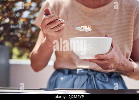 Petit déjeuner sur le balcon. Prise de vue courte d'une femme âgée méconnue qui appréciait son petit déjeuner tout en étant assise sur le balcon à la maison. Banque D'Images