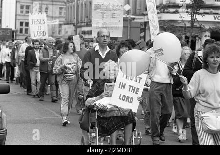 Clowns, poussettes et choeurs se sont tous avéré pour stimuler la deuxième marche annuelle pour Jésus. Des centaines de churchgoers locaux ont assisté à la marche, l'un des nombreux qui se tiennent dans tout le pays pour diffuser le message du christianisme. Le thème de la marche interconfessionnelle de cette année était le rôle de la religion dans l'éducation des enfants. Les marcheurs ont suivi un itinéraire depuis Greenhead Park, à travers le centre-ville, chantant des hymnes et distribuant des tracts. À la suite de la marche, le prédicateur Daniel Cozens parlera plus tard dans le mois à l'église méthodiste Holmfirth et à l'église Elim. 15th septembre 1990. Banque D'Images