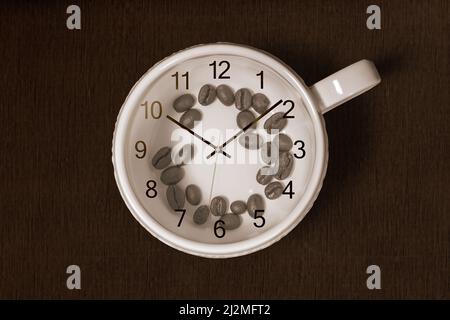 Tasse à café avec grains de café à l'intérieur et horloge sur fond sombre. Concept de l'heure du café Banque D'Images